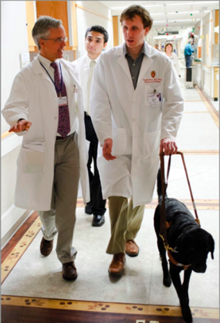 With guide dog Bella leading the way, Tim Cordes talks with physician Michael Peterson, left, and medical student Dhaval Desai, behind, as they do a morning round of patient consultations at UW Hospital.